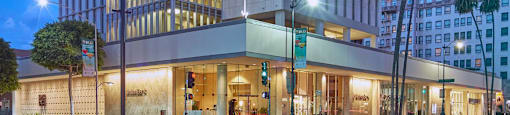 A building with a white facade and large windows is illuminated from within at night.