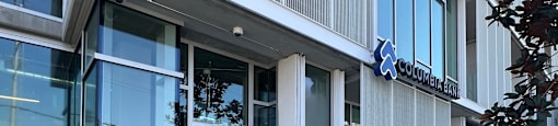 The image shows the front of a building with a glass door and a sign that reads "Columbia Bank."