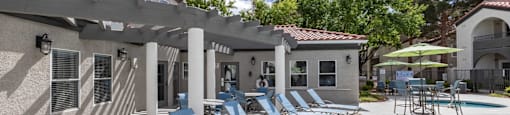 A sunny day at the poolside with chairs and umbrellas.