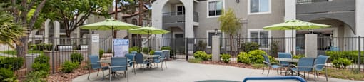 A pool area with a hot tub and chairs in front of a building.