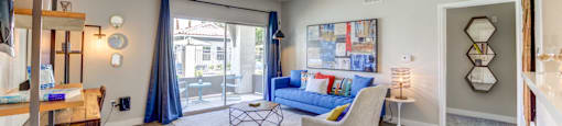 A living room with a blue couch and a white chair.