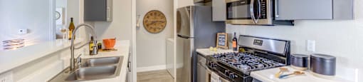 A modern kitchen with stainless steel appliances and a clock on the wall.