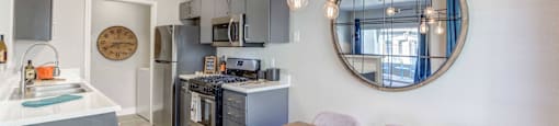 A modern kitchen with a wooden table and grey chairs.