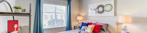 A bedroom with a bed, nightstand, and a fan.