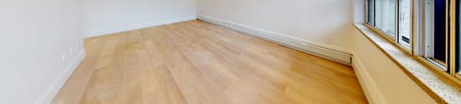A room with wooden floors and a window on the right side.