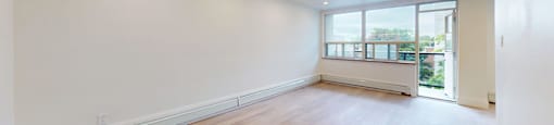 A large empty room with wooden floors and a window.