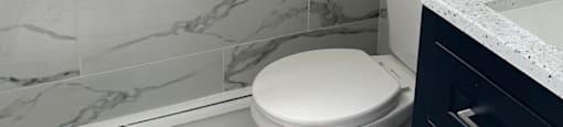 A white toilet in a bathroom with marble tiles.