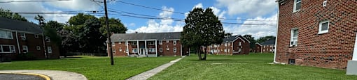 A grassy area in front of a brick building with a tree in the middle.