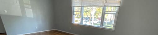 A room with wooden flooring and a window with blinds.