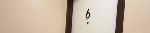 A door with a number 6 on it is slightly ajar.