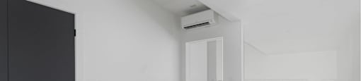 A black wardrobe is on the left in a room with a white wall and a window.