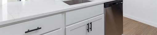 A kitchen with white cabinets and a stainless steel dishwasher.