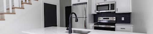 A kitchen with a white countertop and black appliances.