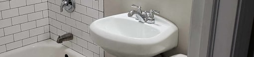 A white toilet sits next to a white sink in a bathroom.