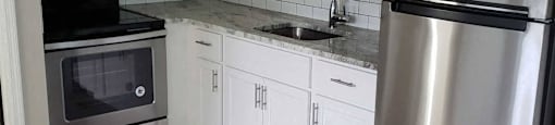 A kitchen with a stainless steel refrigerator, microwave, oven, and cabinets.