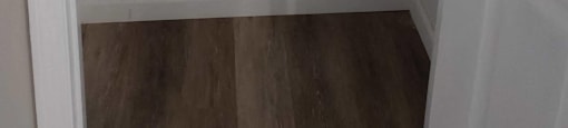 A white door is open to a room with a wooden floor.
