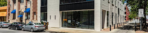 A modern building with a black and white facade is situated on a street corner with cars parked in front.