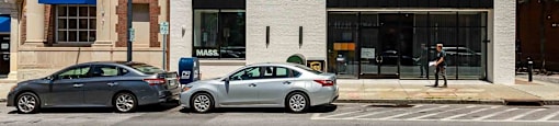 Two cars parked in front of a building with a sign that reads "MASS".