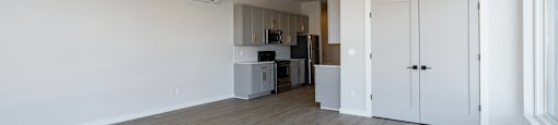 A spacious room with a kitchen area in the background.