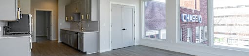 A spacious, empty room with light wood flooring and white walls.