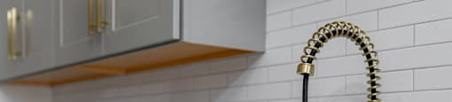 A kitchen sink with a gold faucet and a white countertop.