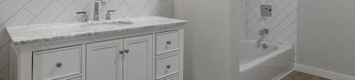 A bathroom with a marble countertop and a round mirror.