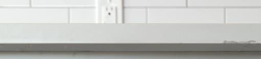A white cabinet with a gold handle and a gold bar above it.