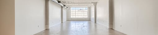 A large, empty room with a cracked floor and white walls.