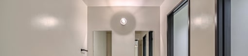 A bathroom with a wooden vanity and a round mirror.