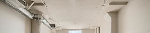 A large empty room with a window and a concrete floor.