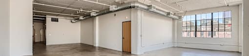 A large, empty room with a concrete floor and white walls.