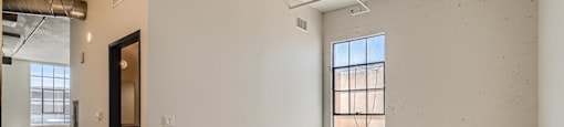 A large empty room with a door and a window.