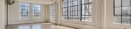 A large, empty room with concrete floors and large windows.