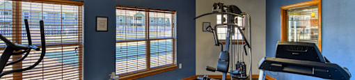 A gym with a treadmill, elliptical trainer, and other exercise equipment.