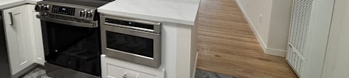 A modern kitchen with white cabinets and a black stove top oven.