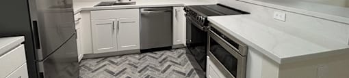 A modern kitchen with a black refrigerator and white cabinets.