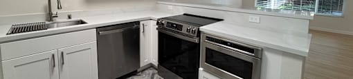 A modern kitchen with white cabinets and a black stove top oven.