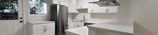 A kitchen with white cabinets and a black fridge.