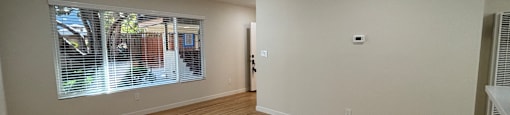 A room with wooden flooring and a window with blinds.