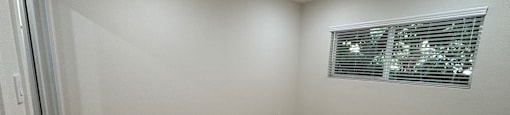 A room with wooden flooring and a window with blinds.