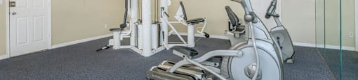 A gym with a treadmill, elliptical trainer and a stationary bike.