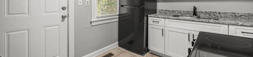 A kitchen with a black refrigerator and white cabinets. at Raleigh Rentals, North Carolina, 27604