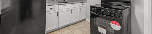 A kitchen with black appliances and white cabinets.  at Raleigh Rentals, North Carolina, 27604