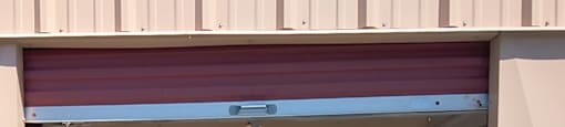 A closed garage door with a red roller.