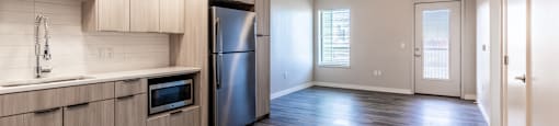 A kitchen with a refrigerator, microwave, and oven.