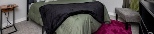 A bedroom with a bed, a chair, and a painting on the wall.