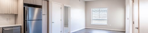 A spacious kitchen with a refrigerator and wooden flooring.