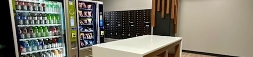 A white table is in the middle of a room with a vending machine to the left.