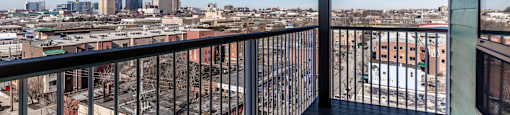 A balcony overlooks a cityscape with buildings and a clear blue sky.