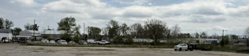 Parking lot with a few cars and a cloudy sky.